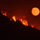 The moon rising over flames on a hilltop near Highway 166 east of Santa Maria, California. (Image: AP)